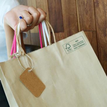 close up of a hand holding a paper shopping bag with FSC MIX Label